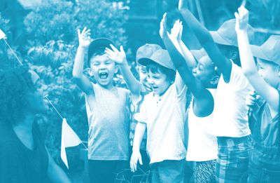 Children outdoors enthusiastically raising their hands